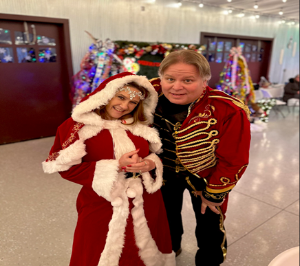 2 people dressed in Christmas clothes posing for a pic